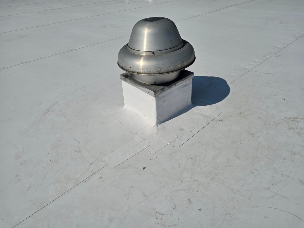Rooftop exhaust fan curb wrapped in new white TPO membrane with welded corner patches