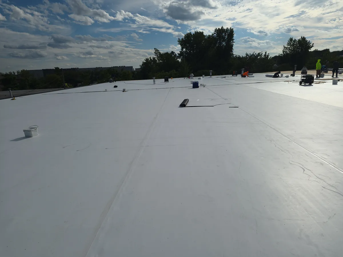 TPO membrane being installed across a large commercial roof while the crew works in the background
