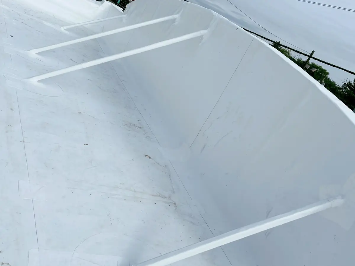 TPO membrane carried up a curved roof edge wall, with the support bars across it wrapped in the same membrane
