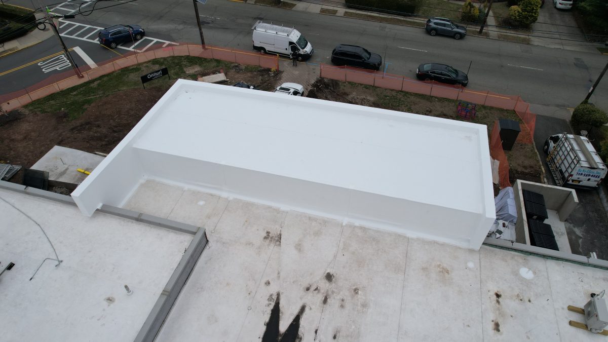 Aerial view of the completed bright white TPO roof on the rooftop addition, with the street below