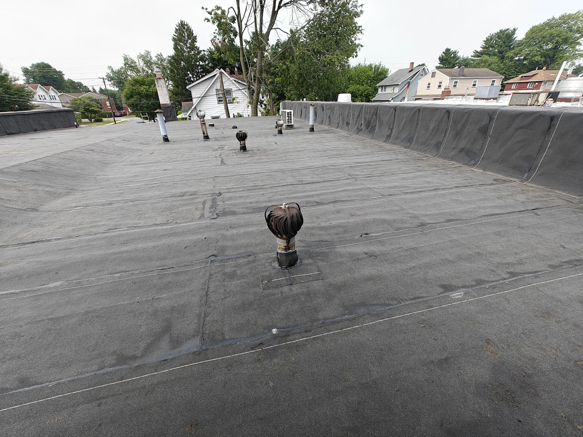 New modified bitumen roof on an office building in Oradell, NJ, with the membrane carried up the parapet wall at the right and turbine vents and vent pipes flashed into the roof