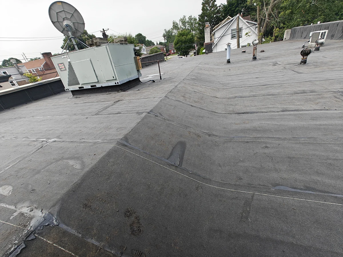Rooftop heating and cooling unit and a satellite dish on a new modified bitumen roof in Oradell, NJ, with turbine vents flashed in beyond