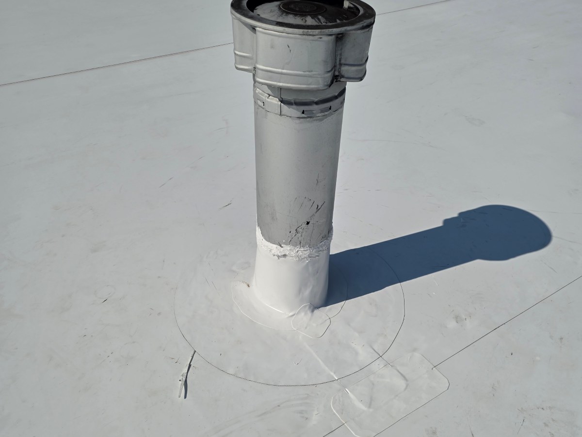 Single pipe penetration flashed with a TPO boot and target patch on a white membrane roof