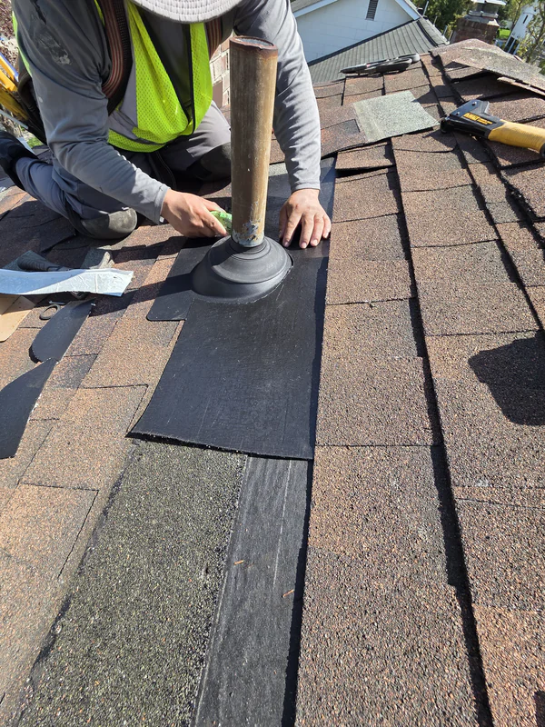 ProTech roofer setting a new pipe boot and fitting shingles around a vent pipe