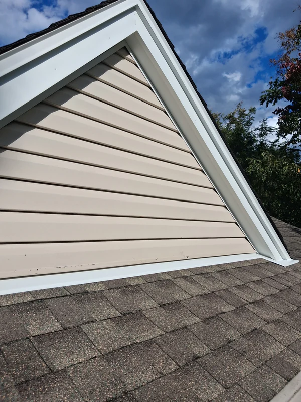 After the repair in Mahwah: new white metal flashing along the bottom of the siding where it meets the shingles, and the rake trim boards capped in white aluminum