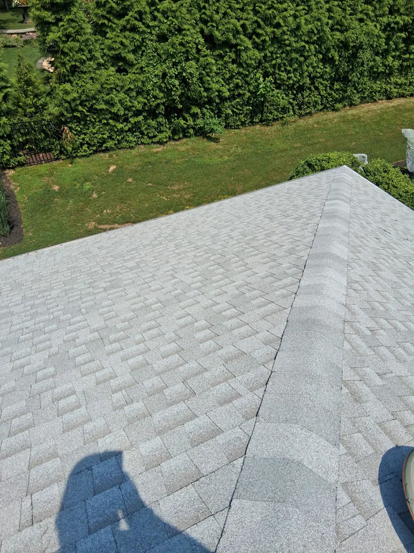 Finished storm damage repair on a light gray shingle roof in West Orange