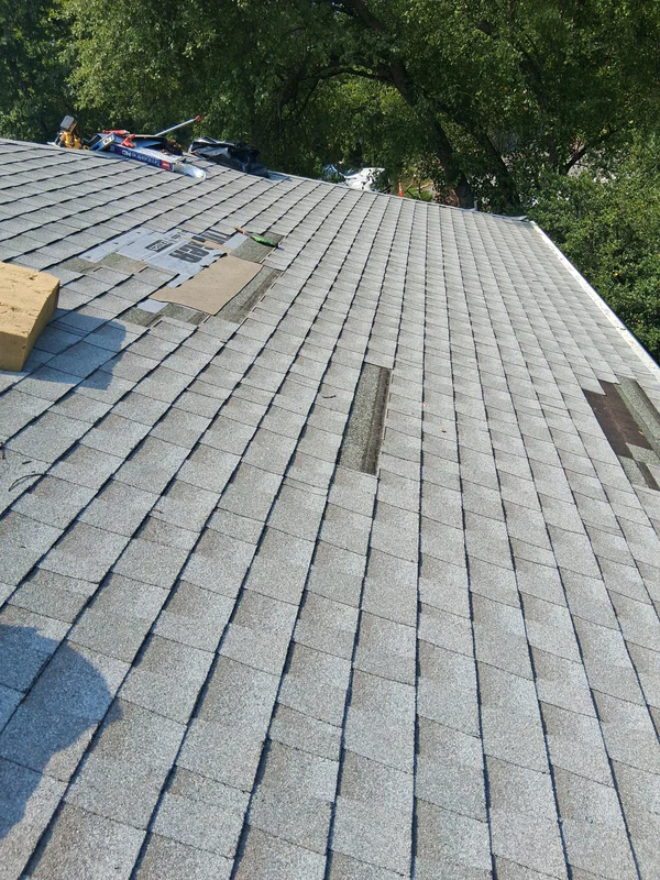 Damaged shingles being replaced across the storm-hit slope of the West Orange roof