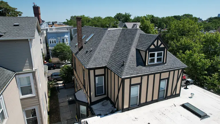New charcoal shingle roof with dormer and skylights on a Tudor-style home
