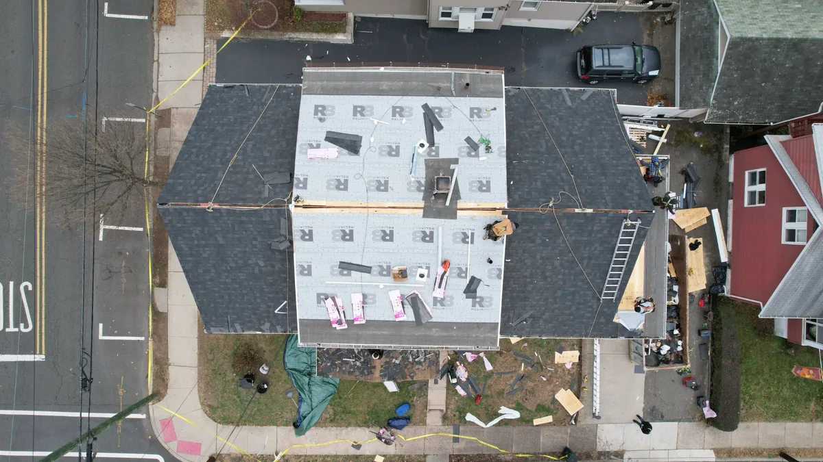 Aerial view of a two-family home with synthetic underlayment installed and shingles going on