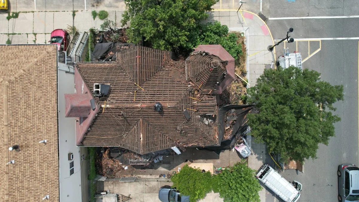 Aerial view of the same Victorian home stripped to bare plank decking with the turret framing exposed